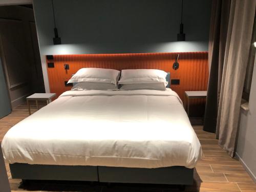 una camera da letto con un grande letto con lenzuola e cuscini bianchi di Materiaprima camere-rooms a Mantova