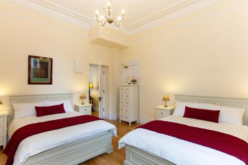 two beds in a bedroom with white and red at Glencourt Apartments in Dublin