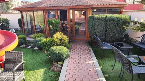a garden with a wooden gazebo with chairs at Family Hotel Kedara in Burgas City