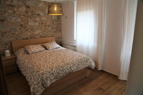 1 dormitorio con cama y pared de piedra en Pescallunes - Idílico apartamento a la orilla del río Brugent, en Sant Feliu de Pallerols