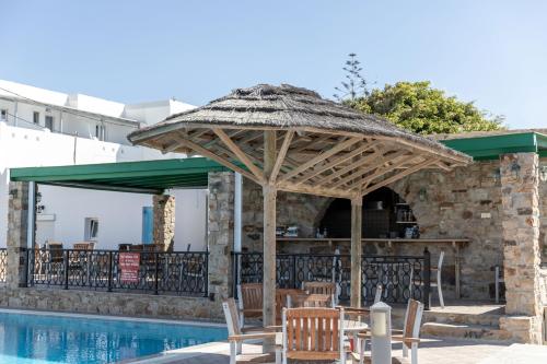 a table and chairs under a straw umbrella next to a pool at Villa Harmony in Agia Anna Naxos