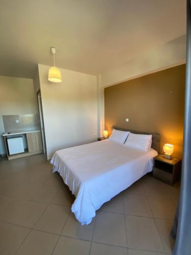 a bedroom with a large white bed with two lamps at Peania Domus in Paianía