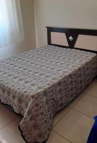 a bed with a black and white bedspread on it at Casa Magnificat in São Thomé das Letras