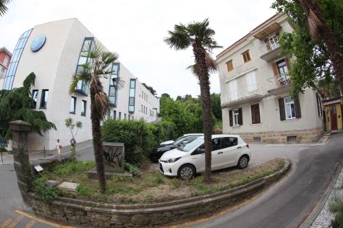 a white car parked next to a building with palm trees at Apartments Morski Svet Portorož in Portorož