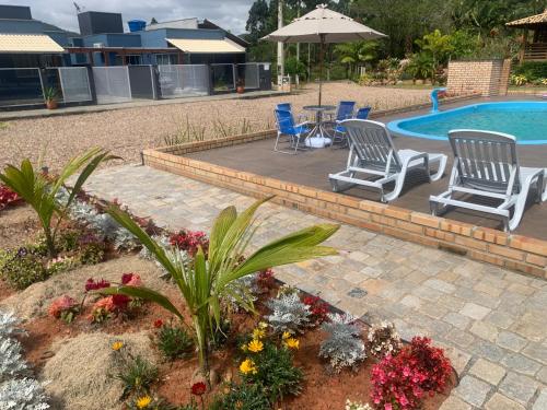 eine Terrasse mit Stühlen und einem Tisch neben einem Pool in der Unterkunft Casa do Lago - Pousada & Casas de Temporada in Penha