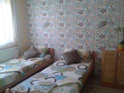 a room with two beds and a wall with flowers at Sobe Zlatna Greda Motorcycle friendly in Novi Sad
