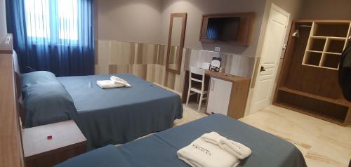 a hotel room with two beds and a television at La Piana Hotel in Tito