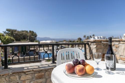 a plate of fruit on a table with a bottle of wine at Villa Harmony in Agia Anna Naxos