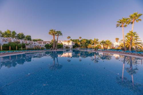 a large swimming pool with palm trees in a resort at Golden Club Cabanas in Cabanas de Tavira