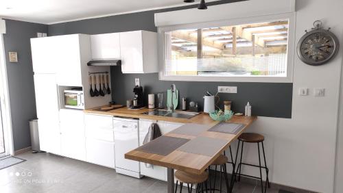 une cuisine avec des armoires blanches et une table en bois dans l'établissement La pause au cub, maison cubique tout confort, à Hinges
