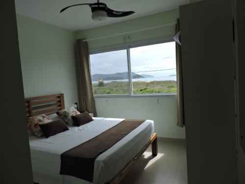 a bedroom with a bed and a large window at Beira Mar Village in Pinheira