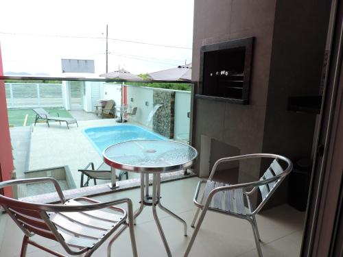 a balcony with a table and chairs and a swimming pool at Beira Mar Village in Pinheira