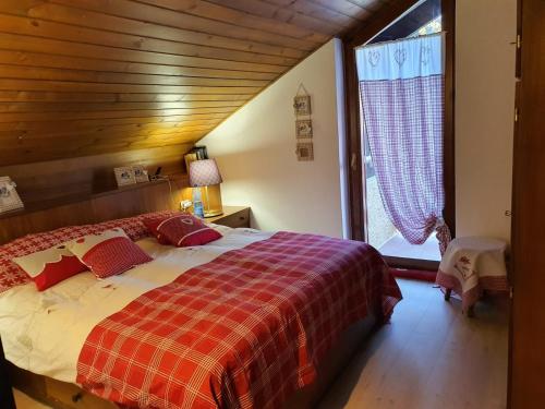 ein Schlafzimmer mit einem Bett und einem großen Fenster in der Unterkunft DELIZIOSA MANSARDA in Madonna di Campiglio