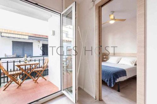 a bedroom with a bed and a balcony with a table at Sitges CENTRAL - En el corazón de Sitges in Sitges