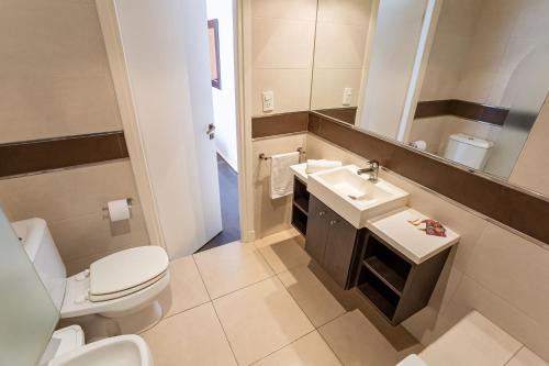 a bathroom with a toilet and a sink and a mirror at Hotel Punta Piedras in Mar del Plata