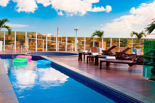 a swimming pool with tables and chairs on a building at Oásis Cabo Frio Hotel in Cabo Frio