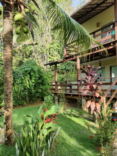a garden with a wooden bench and a palm tree at Charme do Dido in Ilha de Boipeba