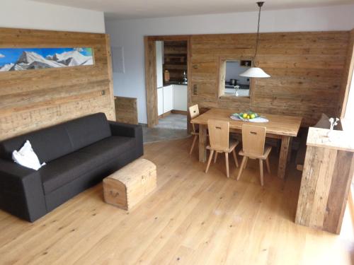 a living room with a black couch and a table at Gasthaus Dorfberg in Kartitsch