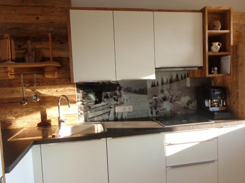 a kitchen with white cabinets and a sink at Gasthaus Dorfberg in Kartitsch