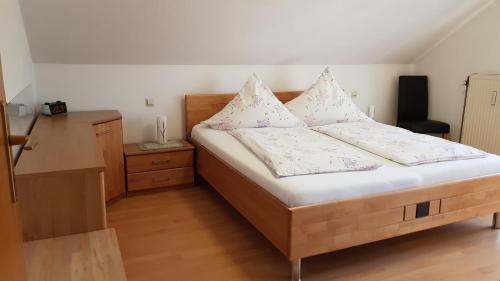 una camera da letto con letto in legno, lenzuola e cuscini bianchi di Ferienwohnung Herrnberg a Baden-Baden