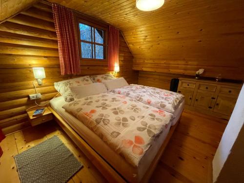 1 dormitorio con 1 cama en una cabaña de madera en Ferienhütte Bosic, en Baierdorf
