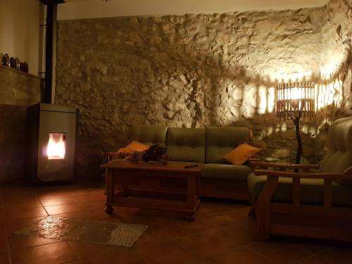 - un salon avec un canapé vert et un mur en pierre dans l'établissement PietraViva Casa vacanze FAICCHIO, NON VISANTI, à Visanti