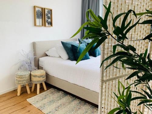 um quarto com uma cama com almofadas azuis e uma planta em Nora Waterview em Breda