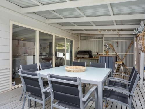 a dining room with a white table and chairs at Decked Out at Dolphin 31 Dolphin Avenue in Carrickalinga