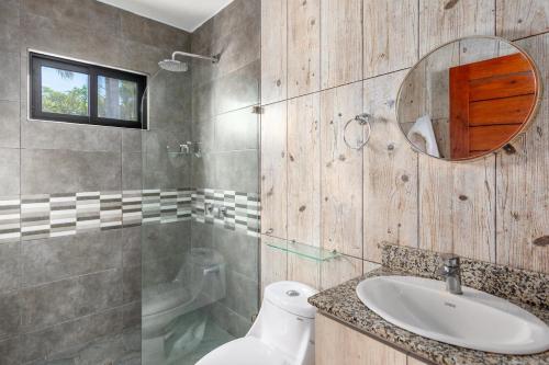 a bathroom with a sink and a toilet and a mirror at Ultramodern Townhome with an Inviting Coastal Design and Lush Outdoor Oasis with a Private Pool in Playa Flamingo