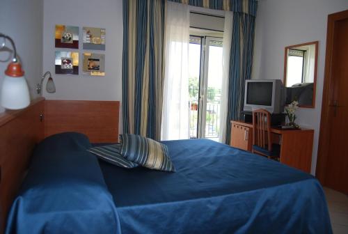 1 dormitorio con 1 cama azul y TV en Telma Hotel, en Terracina