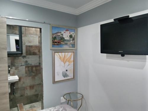 a living room with a flat screen tv on a wall at Dante Guest house in Alberton