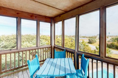 a table and chairs on a balcony with windows at Sun Phun #10HH in Hatteras