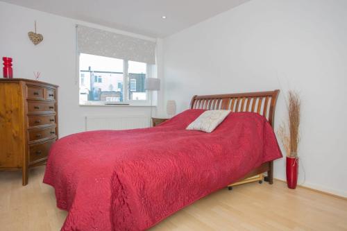 a bedroom with a red bed with a dresser and a window at Stunning 3 Bedroom House with Garden in Battersea in London
