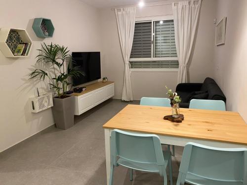 a living room with a table and blue chairs at מעבר לאופק in Yeroẖam