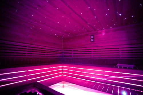 a room with pink lights in a room with a bench at Varga Vendégház in Tiszakécske