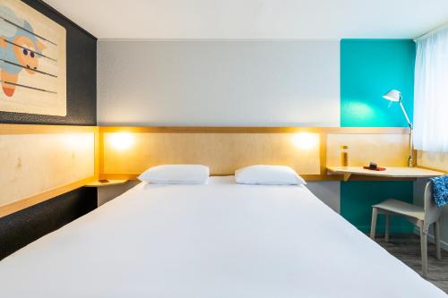 a bedroom with a large white bed and a desk at greet hôtel Angoulême in Saint-Yrieix-sur-Charente