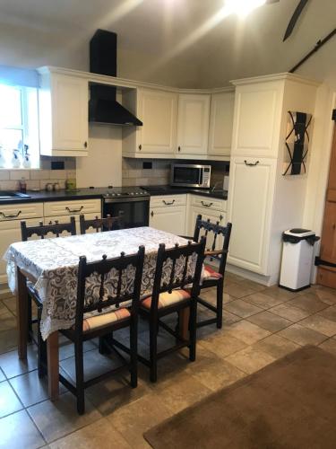 a kitchen with a table and chairs and a kitchen with white cabinets at The Stables in Ashover
