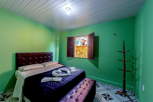 a bedroom with a bed with green walls and a window at Huisje Van Kuringen in Guaramiranga