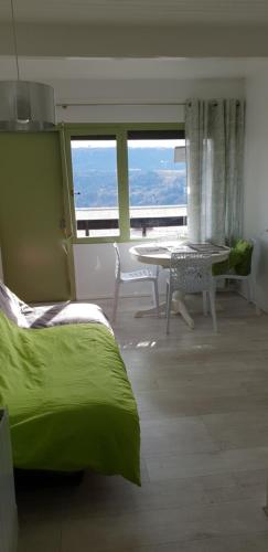 uma sala de estar com uma mesa e uma cama verde em DUPLEX 4 pers super murat 1200 m alt prox mont dore bourboule sancy em Murat-le-Quaire