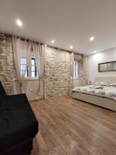 ein Schlafzimmer mit einem Bett und einer Steinmauer in der Unterkunft Sebenico Luxury Rooms in Šibenik