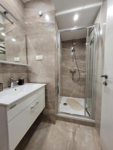 een badkamer met een douche en een witte wastafel bij Sebenico Luxury Rooms in Šibenik