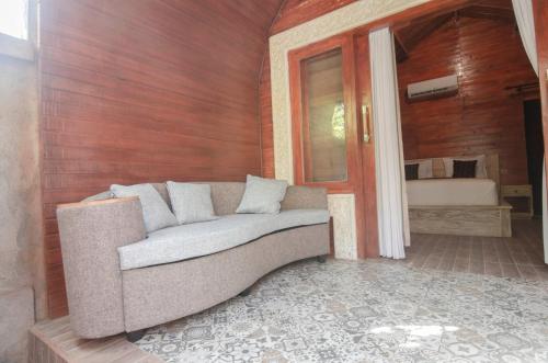 a couch sitting in a room with a bedroom at Kubu Kayana Batuan in Sukawati