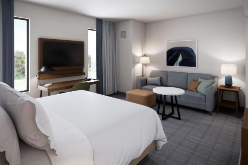 een hotelkamer met een bed, een bank en een televisie bij Staybridge Suites - Colorado Springs NE Powers, an IHG Hotel in Colorado Springs