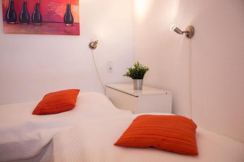 Habitación con 2 camas individuales y almohadas de color naranja. en Haus-am-Deich-Wohnung-9 en Dahme