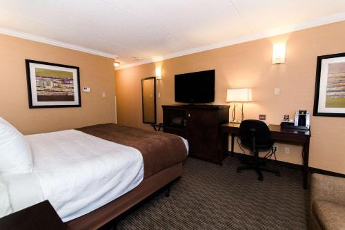 a hotel room with a bed and a desk with a television at Best Western Plus Dryden Hotel and Conference Centre in Dryden