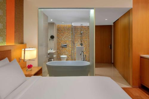 a bedroom with a bed and a tub in a bathroom at Radisson Blu Hotel Guwahati in Guwahati