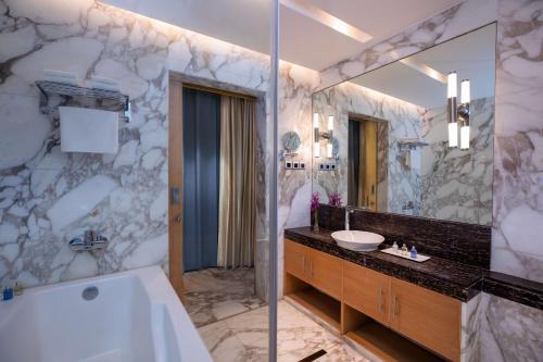 a bathroom with a tub and a sink and a mirror at Radisson Blu Marina Hotel Connaught Place in New Delhi