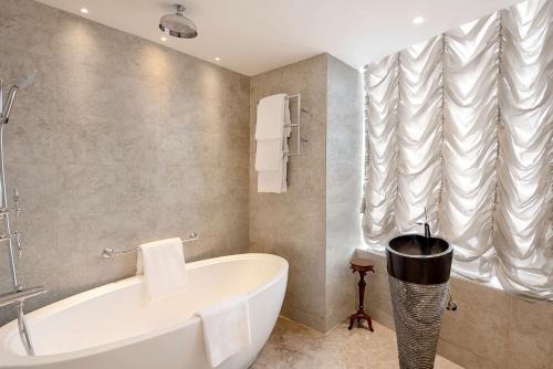 a bathroom with a white tub and a window at Radisson Blu MBD Hotel Noida in Noida