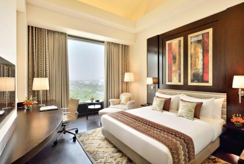 een hotelkamer met een groot bed en een bureau bij Radisson Noida in Noida