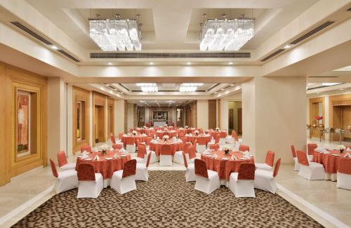 a large banquet hall with tables and chairs and chandeliers at Radisson Noida in Noida